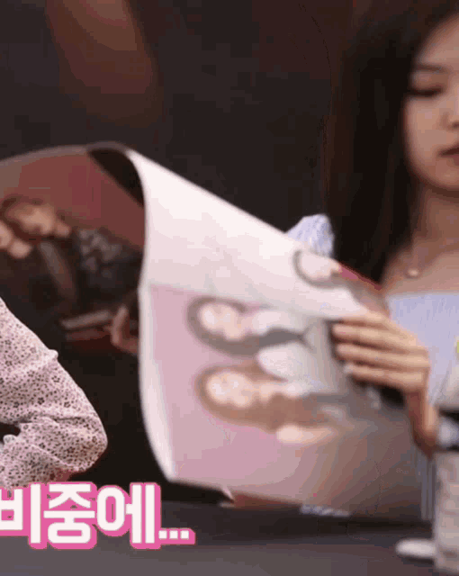 a woman is holding a fan with a picture of three women on it