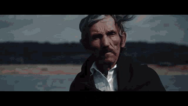 a man in a black coat stands in front of a body of water with the words czarnoksiejniku written below him