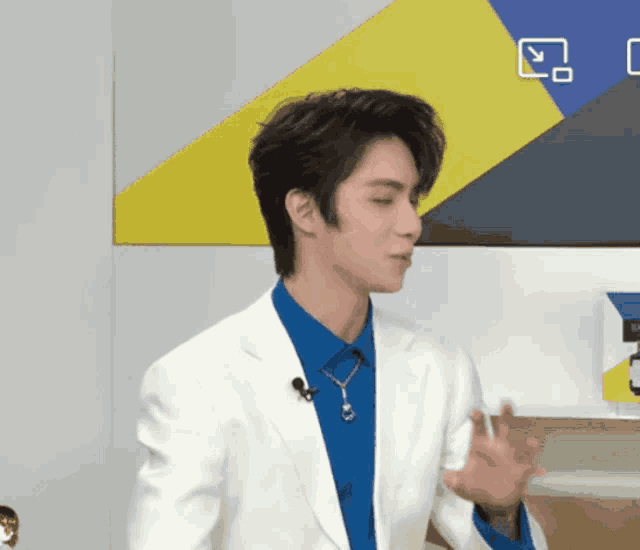 a man wearing a blue shirt and a white jacket with a microphone