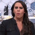 a woman is making a funny face while standing in a kitchen .