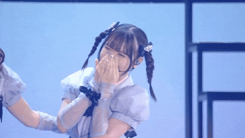 a girl with pigtails is covering her mouth with her hand