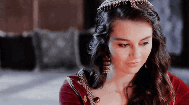 a woman wearing a red dress and a tiara looks down
