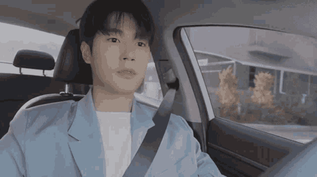 a young man is sitting in the back seat of a car looking out the window .