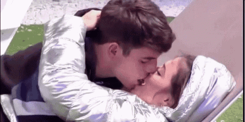 a man and a woman are kissing each other while laying on the ground .