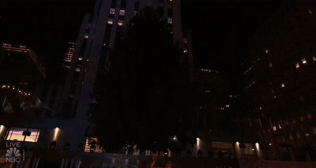 a large christmas tree is lit up in front of a building that says nbc