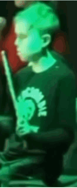 a person in a green shirt is holding a drum stick
