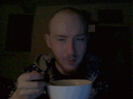 a man with a shaved head is eating from a bowl with a spoon