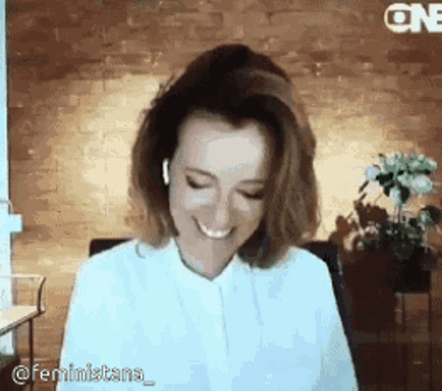 a woman in a white shirt is smiling and wearing ear buds .