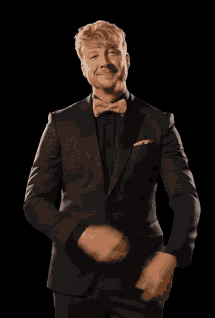 a man in a suit and bow tie is making a funny face