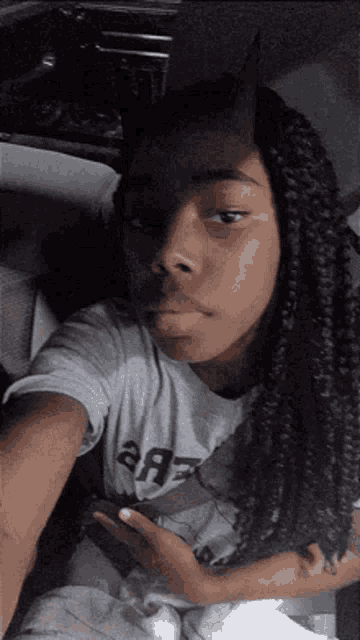 a girl with braids and horns is taking a selfie in a car