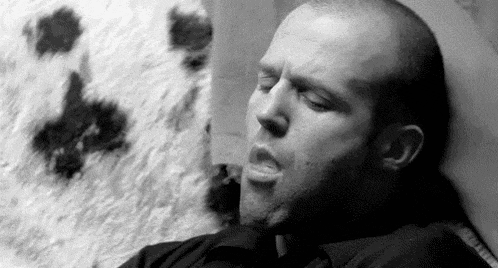 a man is smoking a cigarette while laying on a bed .