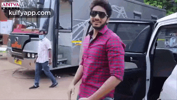a man wearing sunglasses and a plaid shirt is getting out of a white car .