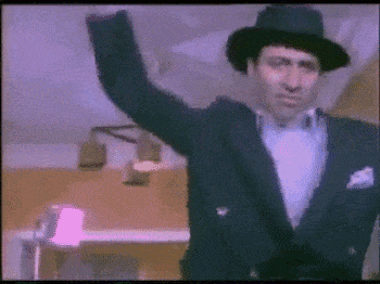 a man in a tuxedo and hat is raising his arm in the air .