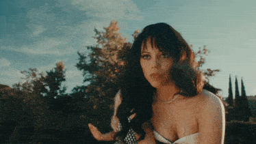 a woman in a white dress with a pearl necklace looks at the camera
