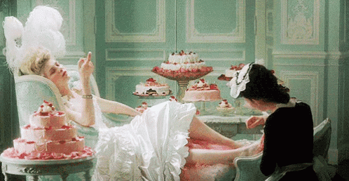 a woman in a white dress is laying on a couch while a maid polishes her nails .
