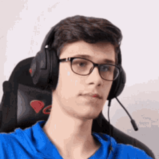 a young man wearing glasses and headphones is sitting in a gaming chair .
