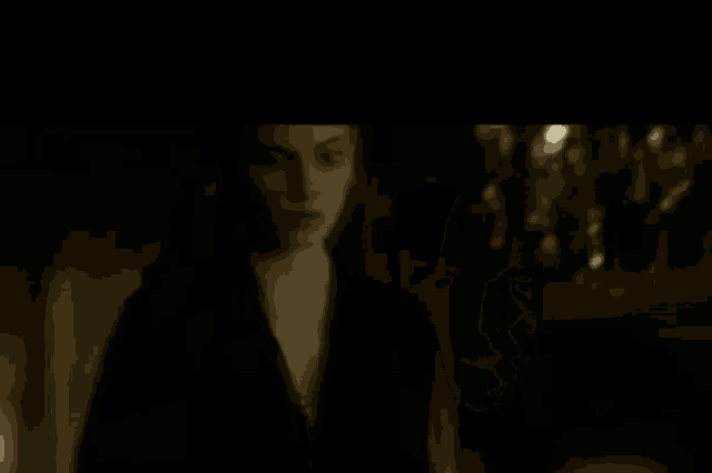 a woman in a black dress is standing in a dark room .