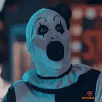 a scary clown with a surprised look on his face is wearing a regal shirt .