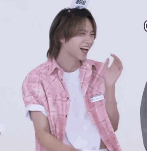 a young man wearing a pink plaid shirt with a name tag that says ' nct dream '