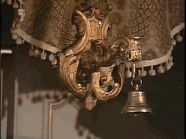 a bell is hanging from a lamp with a floral pattern on it