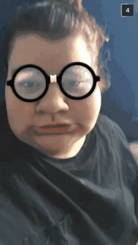 a woman wearing glasses and a black shirt has the number 4 on the bottom right