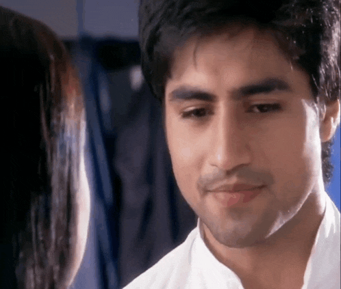 a man in a white shirt is looking at a woman in a blue room .