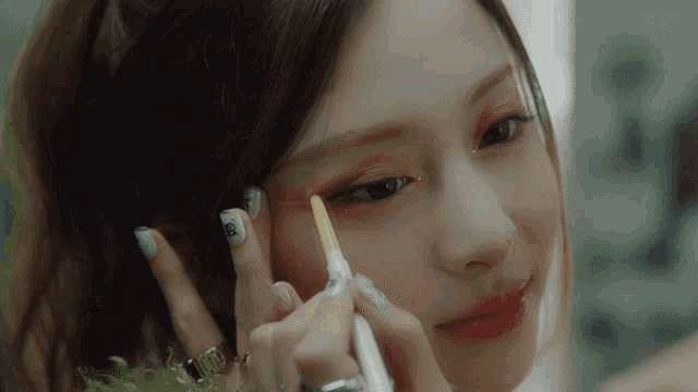 a woman with a ring on her finger is applying makeup