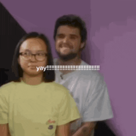 a man and a woman are standing next to each other and the woman is wearing glasses and a yellow shirt .