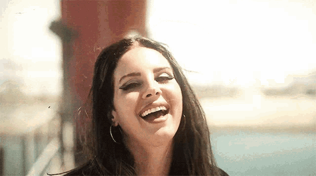 a close up of a woman laughing with her mouth open in front of a water tower .