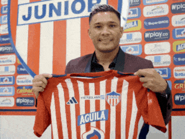 a man is holding up a red and white striped shirt that says aguila