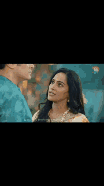 a man in a blue shirt is standing next to a woman in a restaurant .