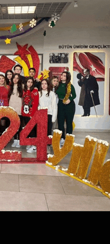 a group of people are posing for a picture in front of a large number 24