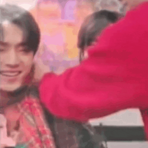 a man in a red shirt is putting a bandage on another man 's face .