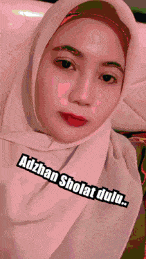 a woman wearing a hijab with adzhan sholat dulu written on the bottom right