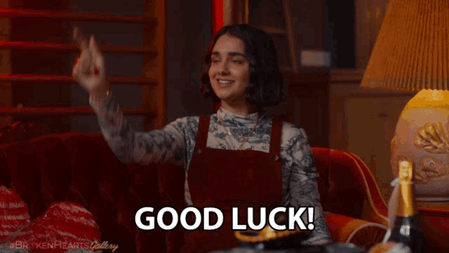 a woman sitting on a couch with a bottle of champagne and says good luck