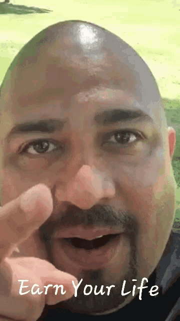 a man with a beard is pointing at the camera with the words " earn your life " written below him