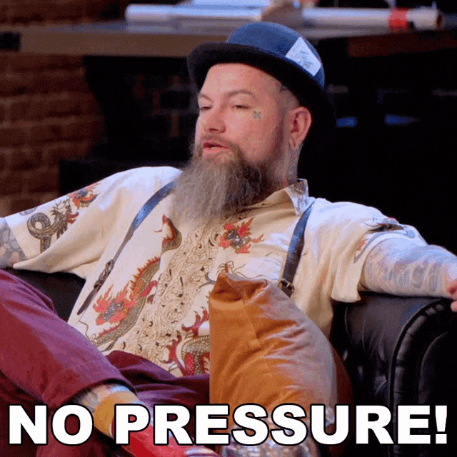 a man with a beard is sitting on a couch with the words no pressure behind him