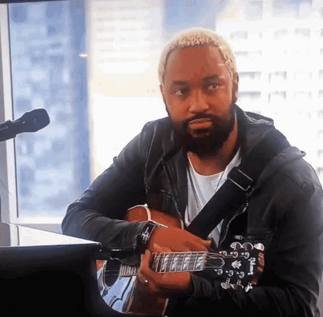 a man playing a guitar with a strap that says yamaha