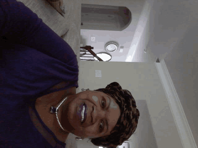 a woman wearing a leopard print head scarf and a pearl necklace smiles for the camera