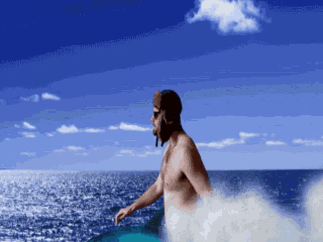 a shirtless man is riding a wave in the ocean