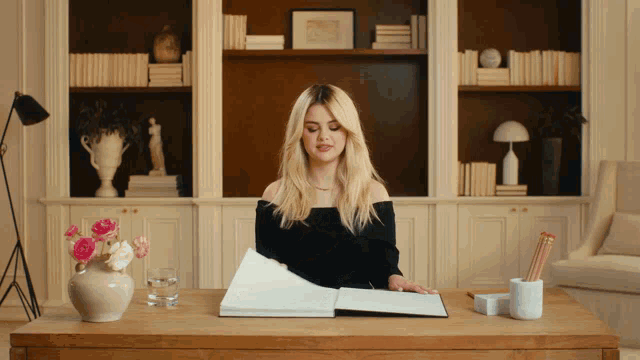 a woman sits at a desk with a book open