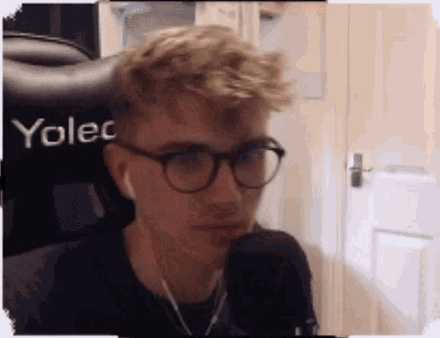 a man wearing glasses and ear buds is sitting in a chair that says yolec