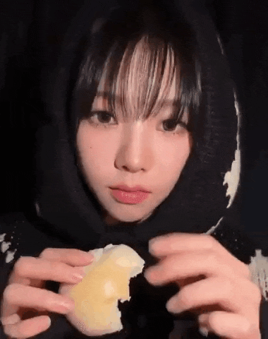 a young girl is eating a piece of cheese .
