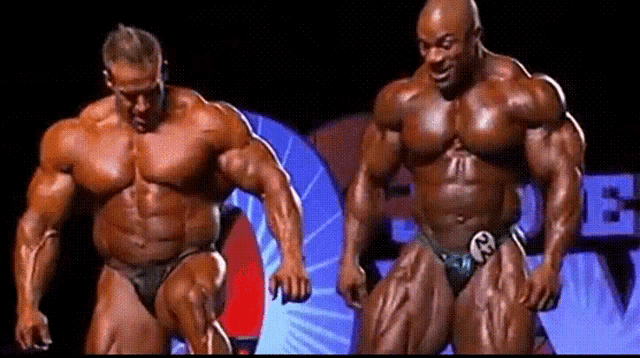 two bodybuilders are standing next to each other with one wearing a number 23 on his belt