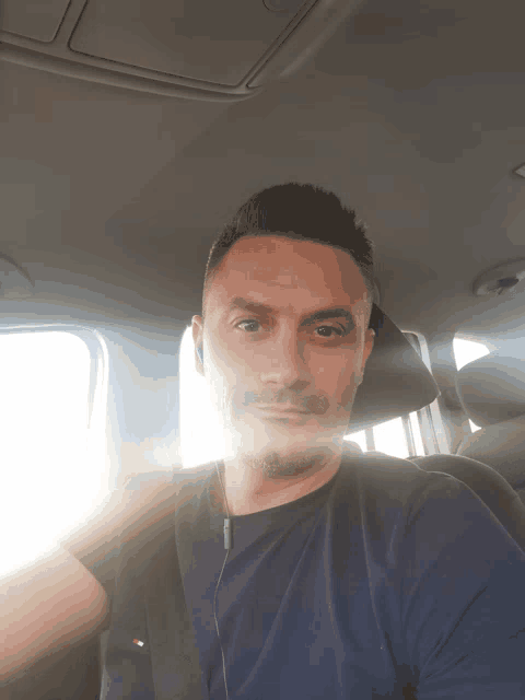 a man wearing a blue shirt is sitting in a car