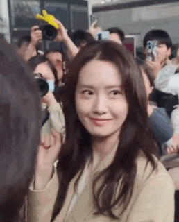 a woman is standing in front of a crowd of people and smiling at the camera .