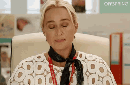 a woman is sitting in a chair with her eyes closed and wearing a scarf around her neck .