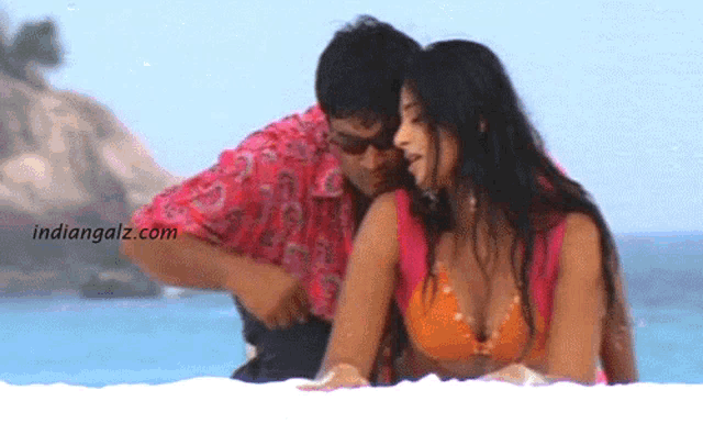 a woman in a bikini is being touched by a man on the beach and the website indiangalz.com is visible