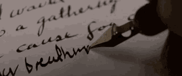 a close up of a person writing with a fountain pen on a piece of paper .