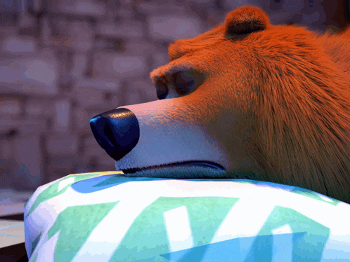 a cartoon bear laying on a pillow with a blue and green leaf pattern